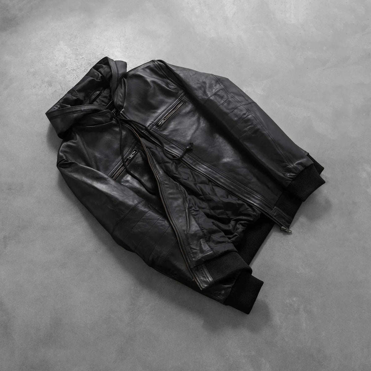 
Perspectiva del modelo vistiendo Bouncer Biz Black Leather Hooded Bomber Jacket en modelo con caída natural bajo luz de día